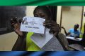 Un assesseur brandissant le bulletin de vote authentifié du candidat du PDG, en août 2016. © AFP
