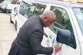 Arnaud Sandri Nombo posant la première vignette sur un taxis bus, le 4 mars 2026 à Owendo. © GabonReview